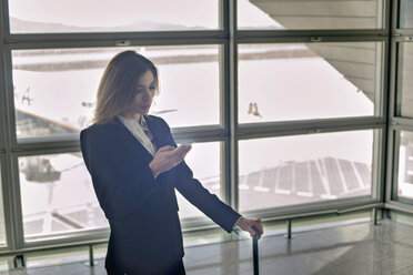 Junge Frau benutzt Smartphone im Flughafen - ISF18687