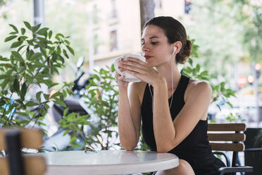 Junge Geschäftsfrau sitzt in einem Café, macht eine Pause und trinkt Tee - KKAF01246
