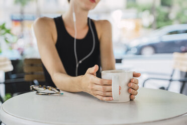 Junge Geschäftsfrau sitzt in einem Café, macht eine Pause und trinkt Tee - KKAF01250