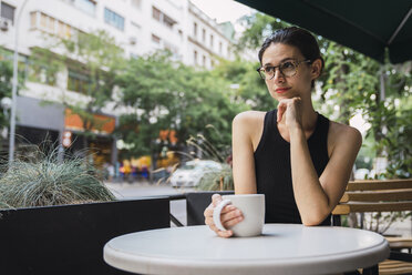 Junge Geschäftsfrau sitzt in einem Café, macht eine Pause und trinkt Tee - KKAF01254