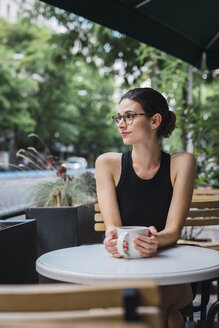 Young businesswoman sitting in coffee shop, taking a break, drinking tea - KKAF01256