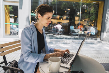 Young businesswoman sitting in coffee shop, using laptop - KKAF01272