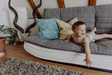 Lachendes Baby auf der Couch liegend - JLOF00120