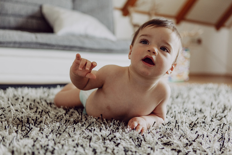 Glückliches Baby spielt auf dem Teppich, lizenzfreies Stockfoto