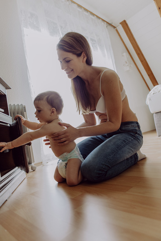 mutter und kleiner Sohn spielen und krabbeln auf dem Boden, lizenzfreies Stockfoto