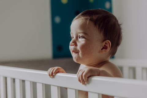 Baby boy standing in his cot stock photo