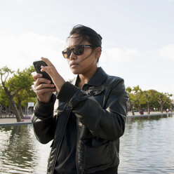 Junge Frau mit Sonnenbrille und Mobiltelefon - ISF18868