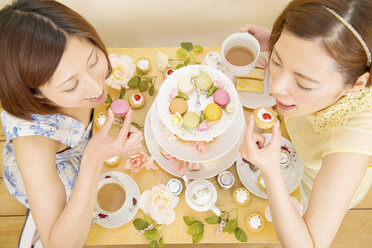 Zwei glückliche Frauen, die sich mit süßen Kuchen verwöhnen - ISF18926