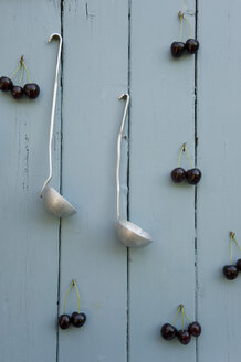 Kirschen und zwei Schöpflöffel hängen an einer Holzwand - GISF00341