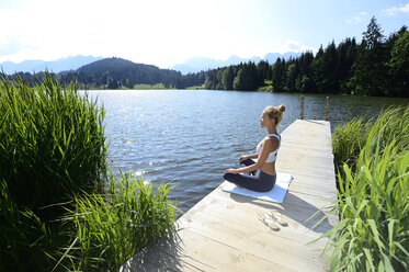 Deutschland, Mittenwald, Frau übt Yoga auf Steg am See - ECPF00234