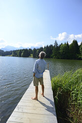 Deutschland, Mittenwald, Rückenansicht eines reifen Mannes, der barfuß auf einem Steg am See steht und sich entspannt - ECPF00237