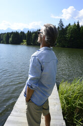 Deutschland, Mittenwald, reifer Mann steht auf Steg am See und entspannt sich - ECPF00238