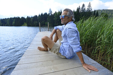 Deutschland, Mittenwald, reifer Mann entspannt auf Steg am See - ECPF00242