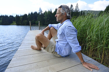 Deutschland, Mittenwald, reifer Mann entspannt auf Steg am See - ECPF00243