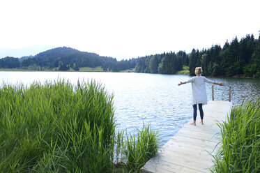 Deutschland, Mittenwald, Rückenansicht einer Frau, die mit ausgestreckten Armen auf einem Steg am See steht - ECPF00245