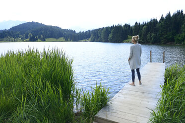 Germany, Mittenwald, woman standing on jetty at lake looking at distance - ECPF00246