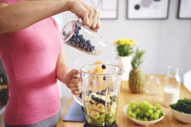 Young woman preparing smoothie in the kitchen, partial view - ABIF00782