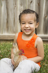Ein junges Mädchen hält ein Huhn. - MINF03004