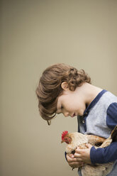 Ein kleiner Junge hält ein Huhn im Arm. - MINF03009