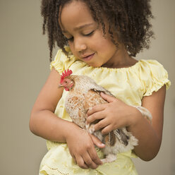 A young girl holding a chicken in her arms. - MINF03011