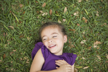 A child lying on her back on the grass. - MINF03020