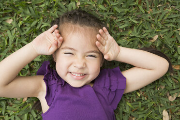 A girl lying on the grass with her hands by her head, laughing. - MINF03022