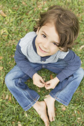 A boy sitting on the grass looking up and smiling. - MINF03024