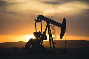 A pumpjack at an oil drilling site at sunset. - MINF03036