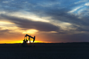 A pumpjack at an oil drilling site at sunset. - MINF03037