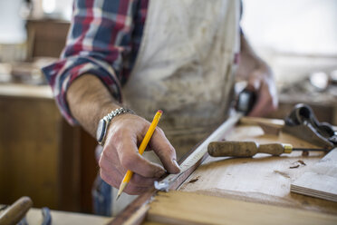 Ein Restaurator für antike Möbel misst ein Stück Holz aus. - MINF03043