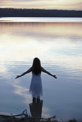 A woman in a white dress in shallow water at dusk - MINF03057