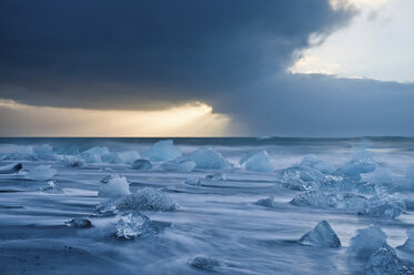 Eisberge am Strand mit stürmischem Himmel, Jokulsarlon, Island - ISF19015