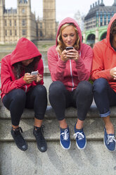 Drei junge Menschen mit Blick auf Mobiltelefone - ISF19036