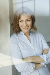 Portrait of smiling businesswoman looking out of window - PNEF00795