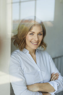 Porträt einer lächelnden Geschäftsfrau hinter einer Fensterscheibe - PNEF00797