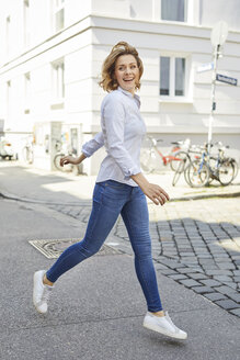 Porträt einer glücklichen Frau beim Überqueren der Straße - PNEF00800