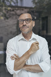 Porträt eines Mannes mit Bartstoppeln hinter einer Fensterscheibe, weißes Hemd und Brille - PNEF00821