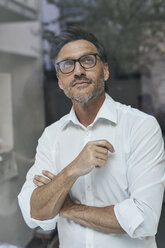 Porträt eines Mannes mit Bartstoppeln hinter einer Fensterscheibe, weißes Hemd und Brille - PNEF00822