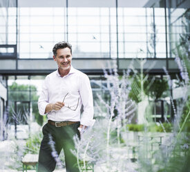 Portrait of smiling businessman outside office building - UUF14668