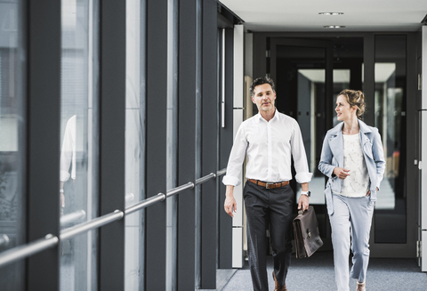 Businesswoman and businessman walking in office passageway stock photo