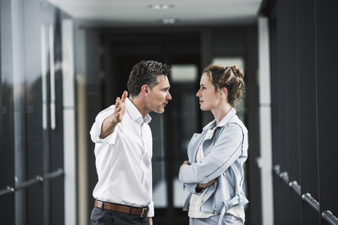 Businesswoman and businessman arguing in office passageway stock photo