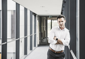 Portrait of confident businessman in office passageway - UUF14724