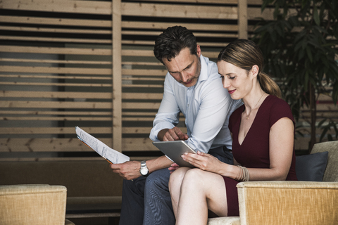 Businesswoman and businessman with tablet discussing in office lounge stock photo