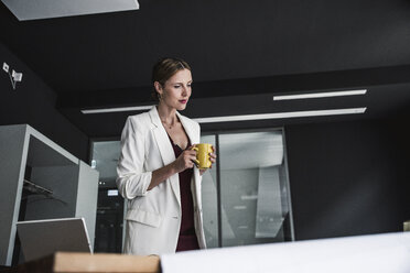 Geschäftsfrau im Büro betrachtet einen Plan auf dem Schreibtisch - UUF14765
