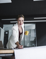 Geschäftsfrau im Büro arbeitet an einem Plan am Schreibtisch - UUF14766