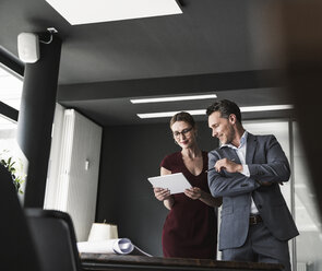 Geschäftsfrau und Geschäftsmann teilen sich ein Tablet im Büro - UUF14778