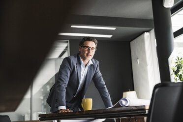 Geschäftsmann im Büro mit Plan auf dem Schreibtisch - UUF14780