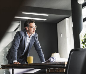 Businessman in office with plan on desk - UUF14781