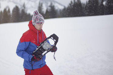 Mann zieht Schneeschuhe an - MMAF00461