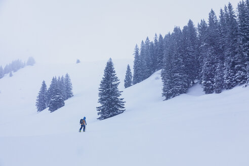 Skifahrer, der bei Schneesturm den Berg hinauffährt - MMAF00463